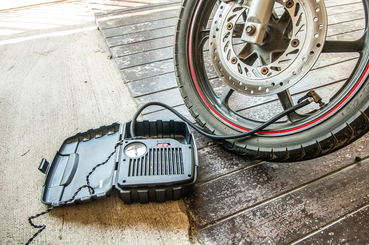 Přenosný kompresor nafukuje pneumatiku motorky